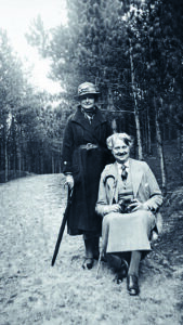 Oude foto met twee vrouwen eentje staand en eentje zittend op een bospad.